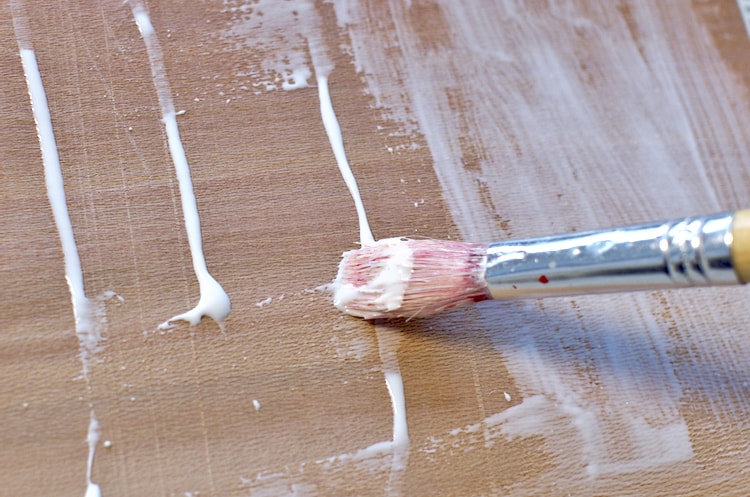 Spreading wood glue with an old brush on a sheet of cherry veneer